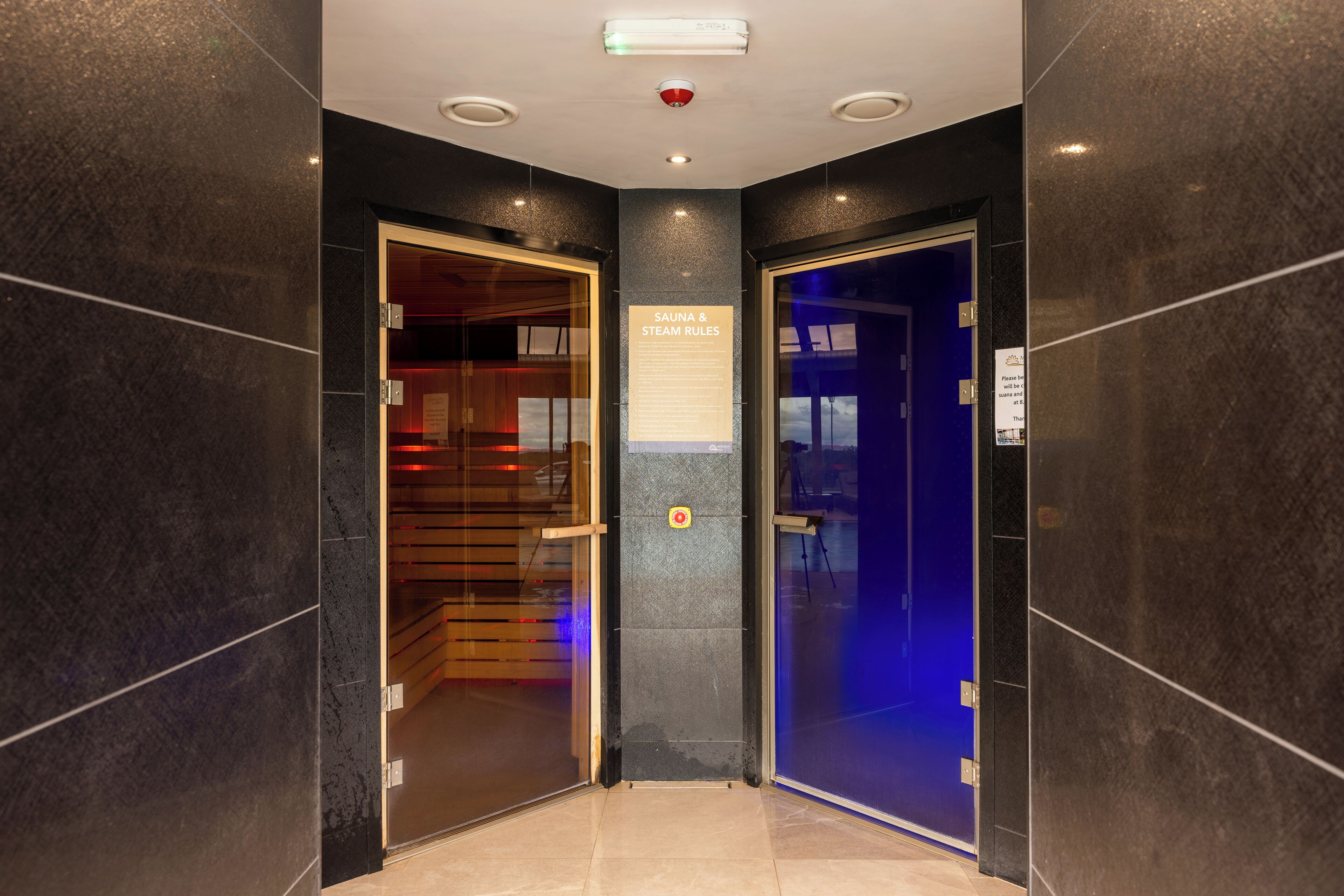 Un hall d’hôtel doté de deux portes, dont l’une mène à un sauna et à un hammam, et l’autre à une salle privée.