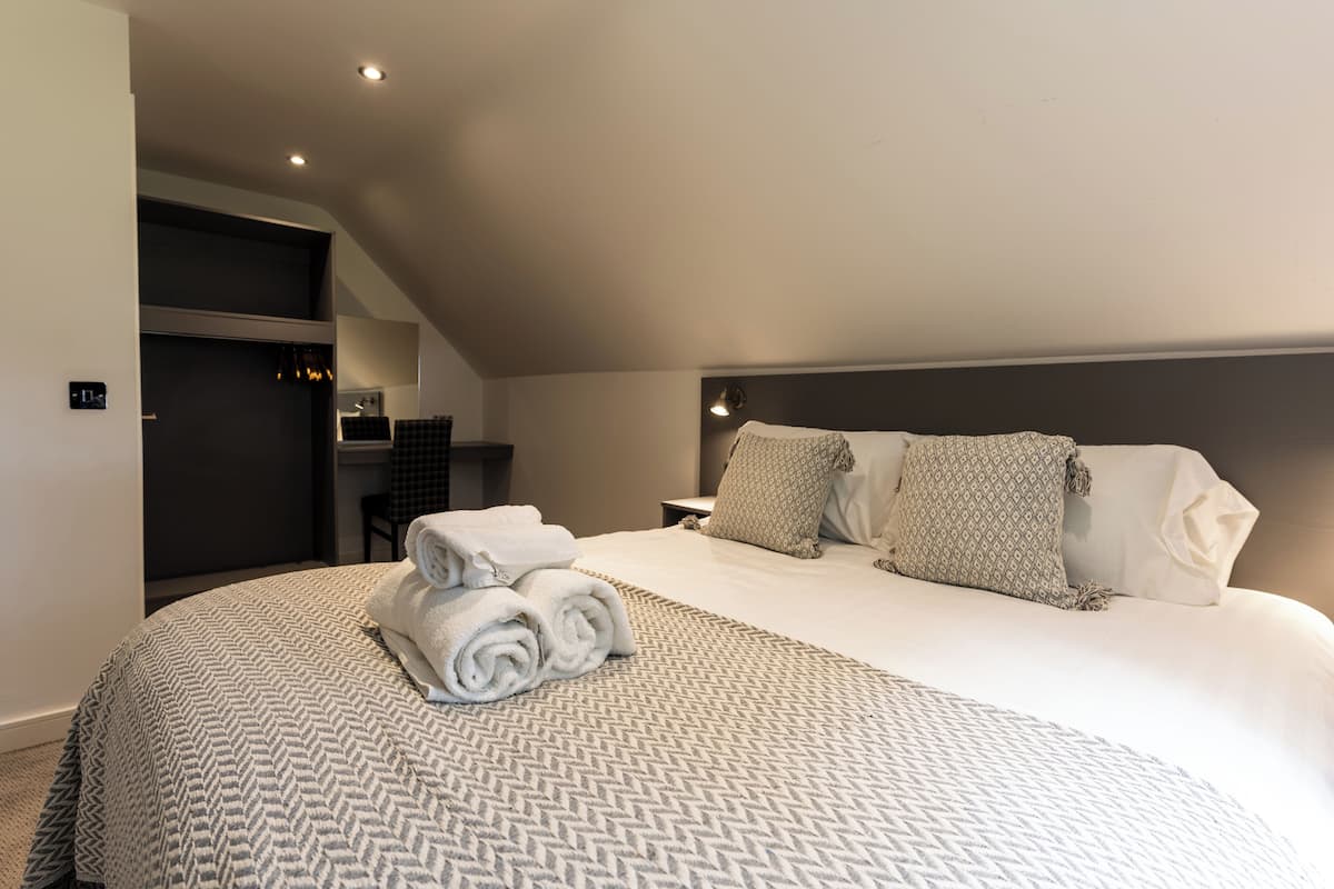 Ein modernes Hotelzimmer mit einem großen Bett, einer Kopfteil und einem kleinen Schreibtisch mit Stuhl.