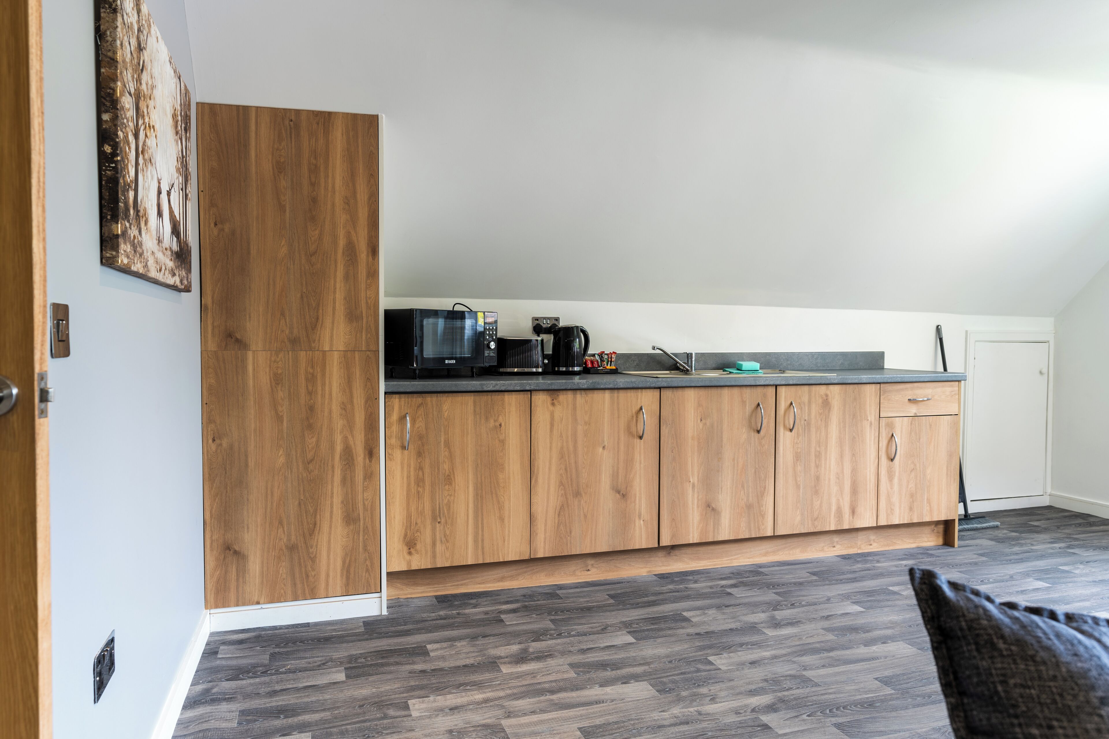 A modern kitchen with wooden cabinets, a microwave, a coffee maker, and a sink.
