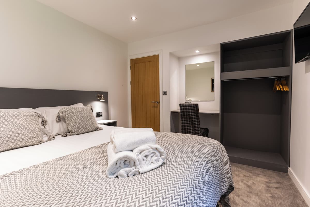 Ein modernes Schlafzimmer mit einem großen Bett, einem Einbauschrank, einem Spiegel und einem kleinen Badezimmer.