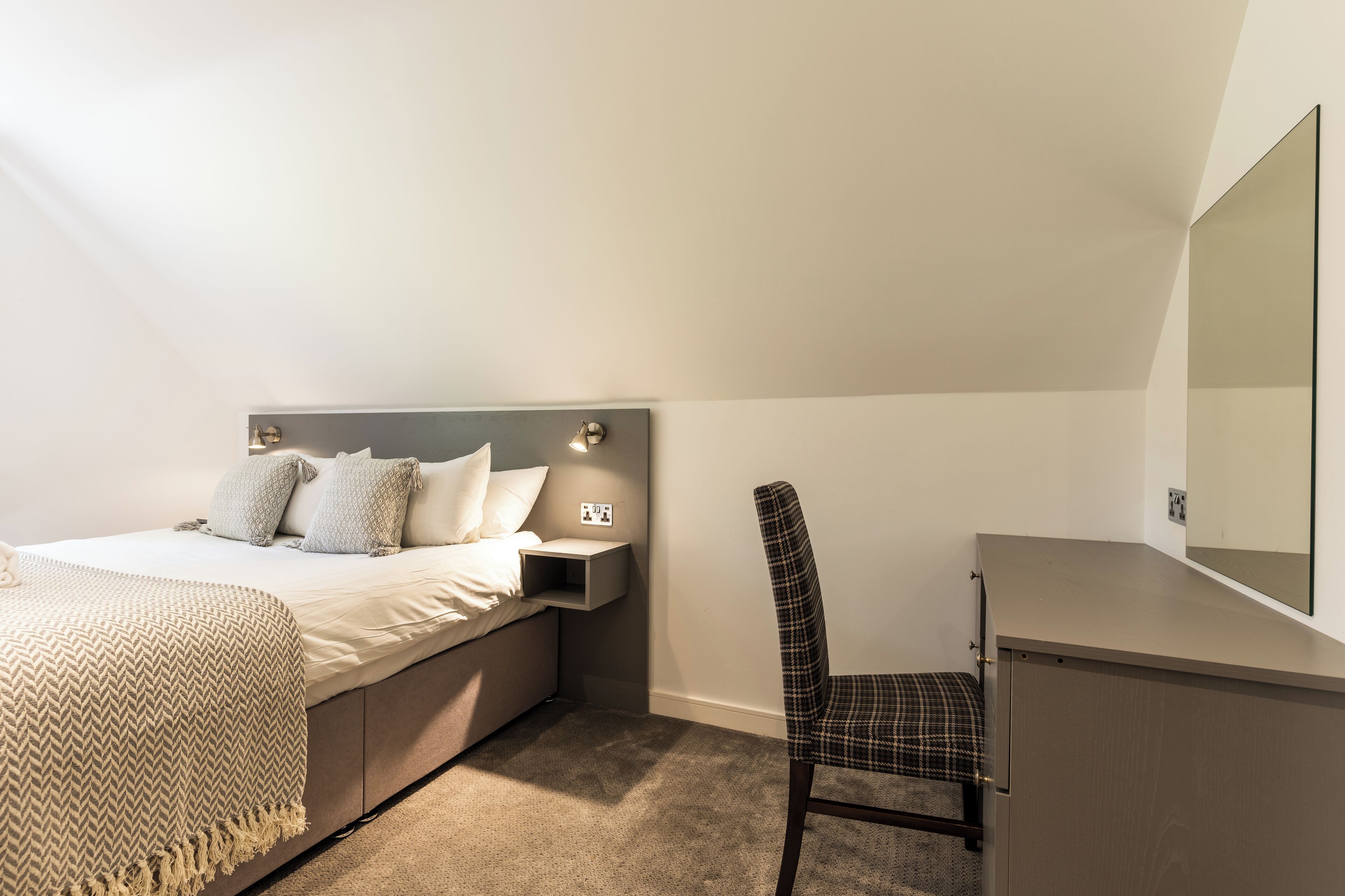 Una camera da letto con un letto, un comodino, una sedia e uno specchio grande.