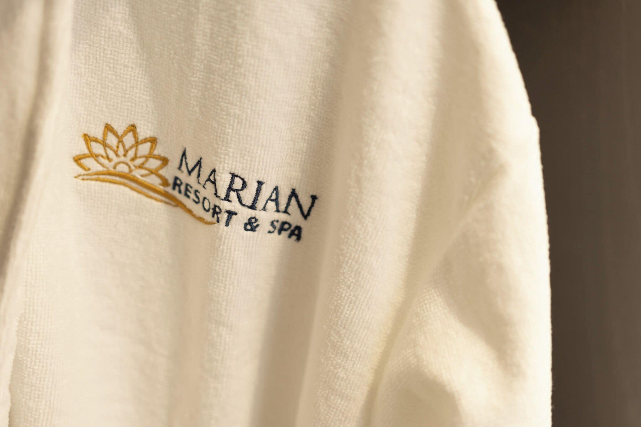 Un tessuto bianco con ricami che riportano la scritta "MARIAN RESORT & SPA".