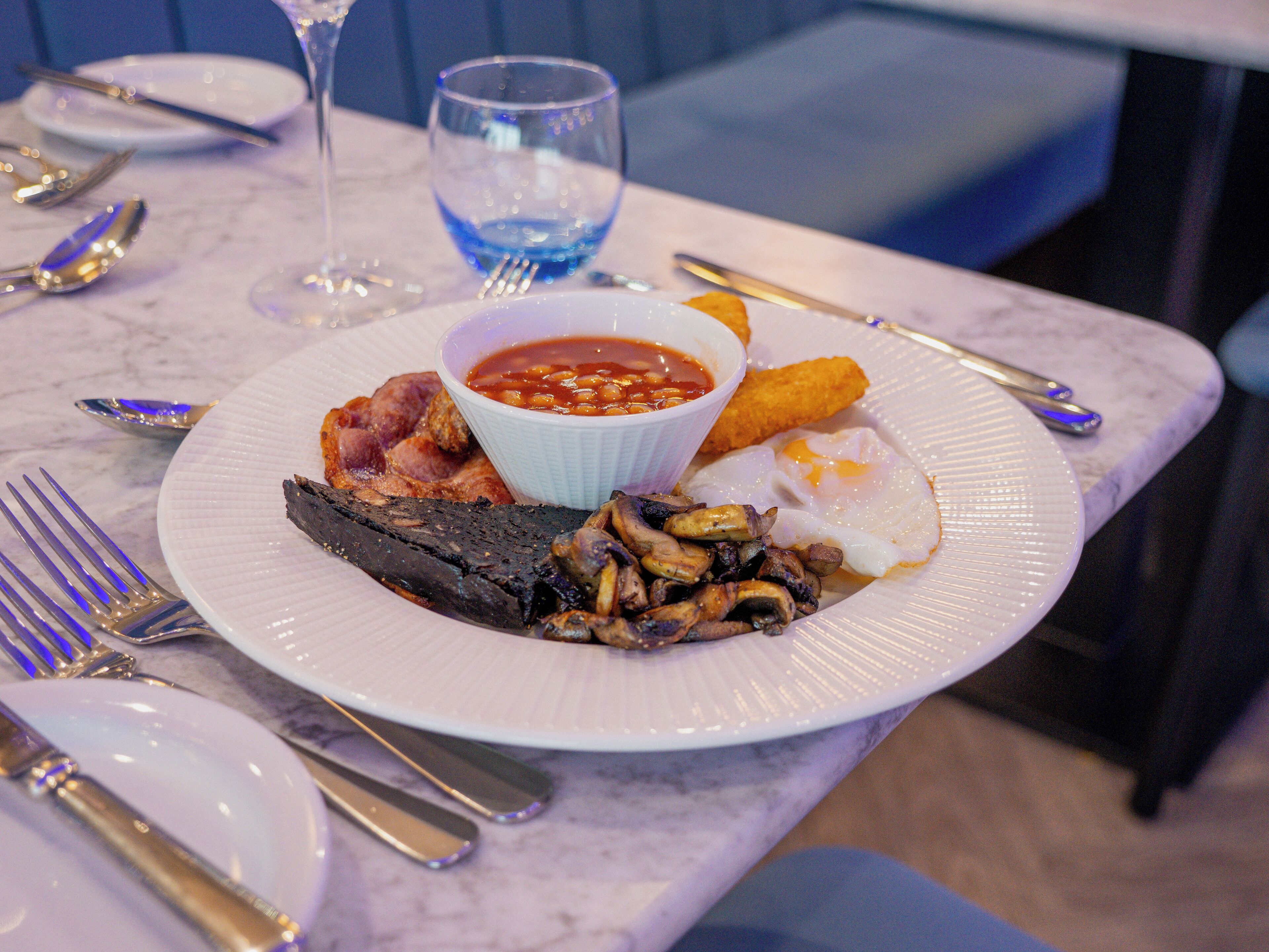A plate of food including fried eggs, beans, bacon, and mushrooms.