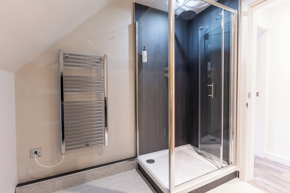 A modern bathroom with a glass shower enclosure, a built-in towel rack, and a visible power outlet. - Marian Resort And Spa (Rhyl)