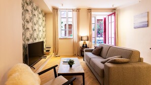 A living room with a sofa, a coffee table, a TV, and a window with curtains.