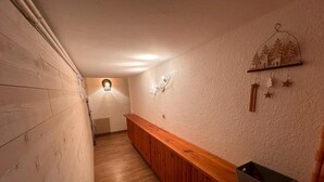 A narrow hallway with wooden paneling, a bench, a radiator, and a wall-mounted light fixture.