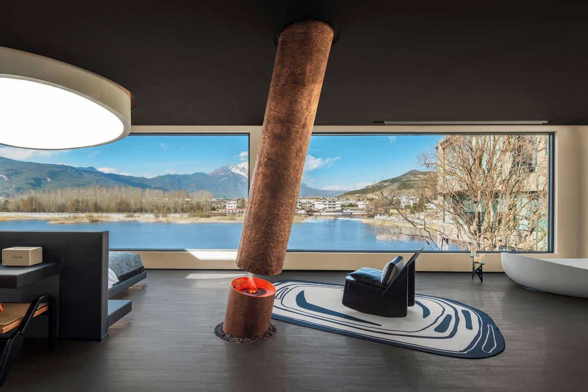 Ein modernes Zimmer mit großem Fenster, Kamin, Schreibtisch und Stuhl.