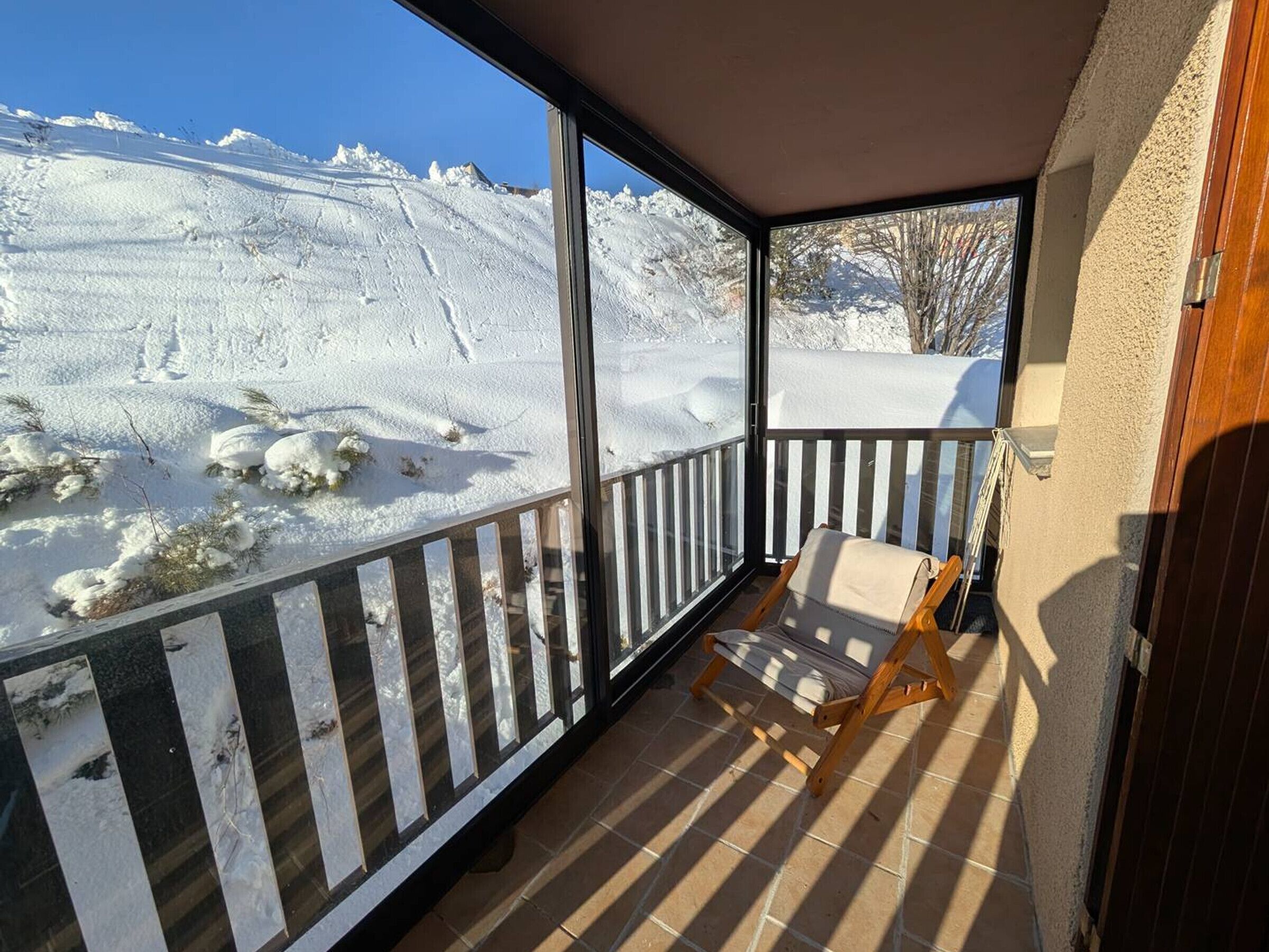 En balkon med en stol, der udover et sneklædt landskab.