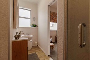 Un baño pequeño con lavamanos, inodoro y una ventana.
