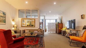 Un salón espacioso con un conjunto de sofás, un sillón rojo, una mesa de centro y una televisión.
