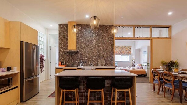 Una cocina moderna con una isla central, taburetes de madera y luces colgantes.
