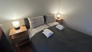 A neatly made bed with plaid bedding, two bedside lamps, and folded towels on the bed. - Modern Room in Apartment With Private Balcony in Beutiful Oslo  (Oslo)