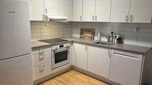 A modern kitchen with white cabinets, a Bosch refrigerator, a built-in oven, a dishwasher, and a wooden cutting board on the countertop. - Modern Room in Apartment With Private Balcony in Beutiful Oslo  (Oslo)