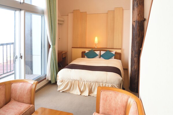 A hotel room with a large bed, a window with curtains, a wooden headboard, and a small table. - SADO Futatsugame View Hotel (Sado)