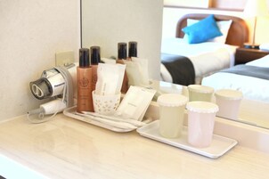 Habitación de hotel con una tocador de baño ordenado, que incluye artículos de aseo, un secador de pelo y una bandeja con velas.
