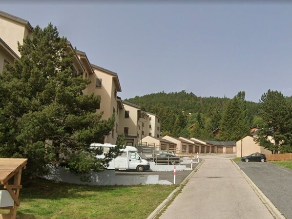 A residential street with apartment buildings, a parked white van, and a car.