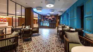 Un hall de hotel con mobiliario de madera, suelo estampado y una zona de bar.