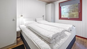 A bedroom with a bed, a window, and a wooden ceiling.