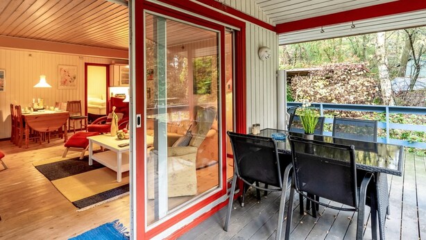 A modern interior with a dining area, a sofa, and a glass door leading to a balcony.