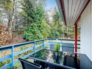 Une table à plateau en verre, sur laquelle est posée une plante en pot, sur un balcon doté de balustrades bleues.