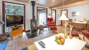 A spacious living room with a TV, fireplace, comfortable seating, and a dining area.