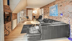 En moderne stue med en sort lædersofa, et sofabord og en murstensvæg.