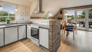 Et moderne køkken med et stort vindue, en murstensvæg og et spiseområde med udsigt.