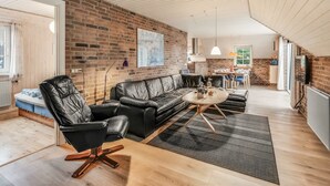 En moderne stue med en murstensvæg, lædersofa og trægulv.