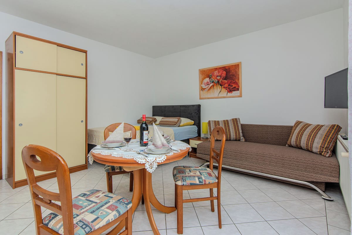 A compact living space with a dining table, chairs, a sofa, and a bed.
