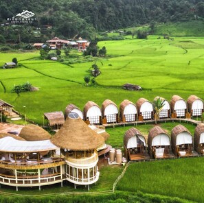 A resort with thatched-roof cottages and a central building with a circular balcony. - Sapanklangna (Bo Kluea)