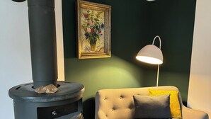 Una stanza con un camino a legna, un divano con cuscini, un quadro incorniciato e una lampada da tavolo.
