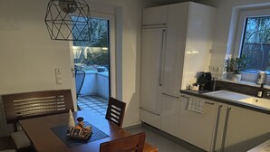 Una cucina moderna con mobili bianchi, un tavolo da pranzo con sedie e una finestra vista alberi.