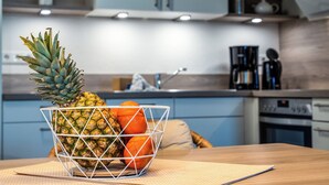 Una cocina con un bol de frutas que contiene una piña y naranjas sobre una mesa de madera.