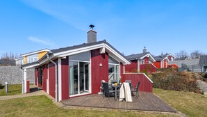 Ein rotes Holzhaus mit einem großen Glasfenster und einer Holzterrasse.