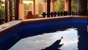 A swimming pool with a covered area and chairs, surrounded by trees and a clear sky. - Hulder- og Trollparken (Senja)