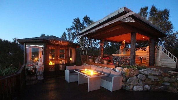 An outdoor patio area with a fire pit, seating, and a covered structure labeled "VALIUM". - Hulder- og Trollparken (Senja)