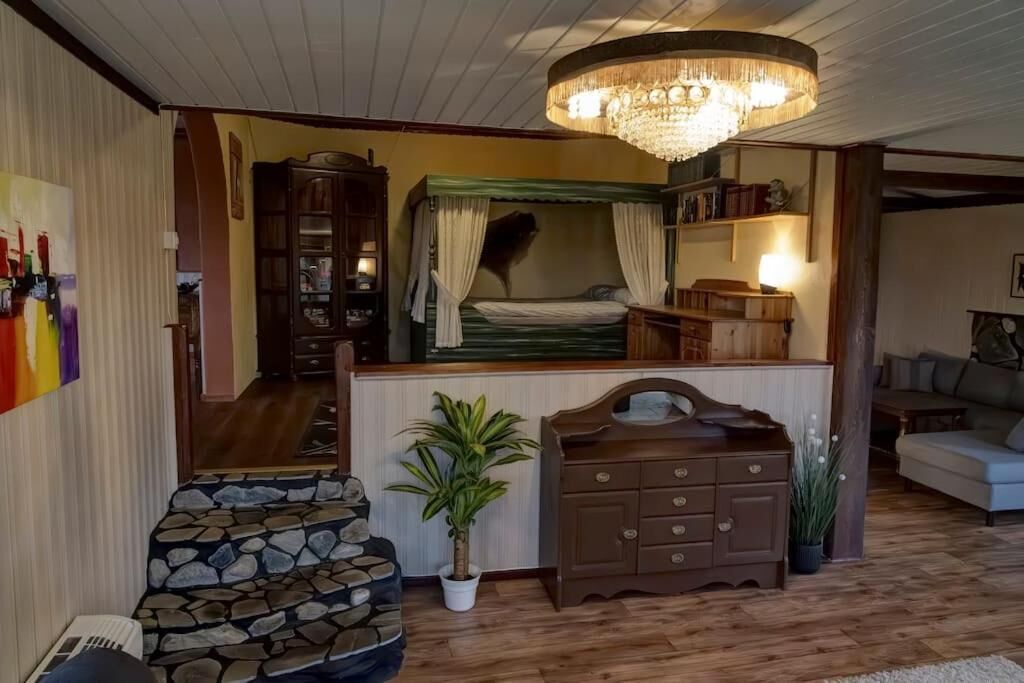 Una habitación acogedora con una cama, un aparador de madera, una araña y un sofá con estampado de piedra.