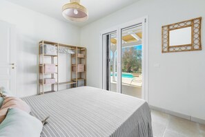 A bedroom with a bed, a wardrobe, and a sliding glass door leading to a pool area. - 4201 Terrazze Ai Demani by Perle di Puglia (Manduria)