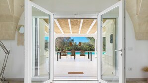 Een modern interieur met een glazen deur naar een buitengebied met een zwembad en zitplaatsen.