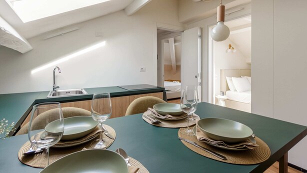 Eine moderne Küche mit Oberlicht, ein Essbereich mit Tisch für vier Personen und ein durchgehender Durchgang zu einem Schlafzimmer.