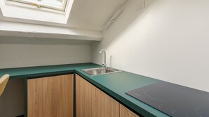 Eine Küche mit Oberlicht, Spüle, Holzschränken und einer schwarzen Induktionskochplatte.