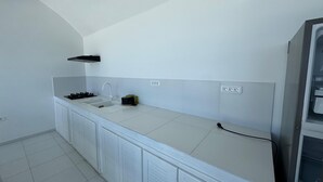 Una cocina con armarios blancos, cocina a gas, lavamanos y horno empotrado.