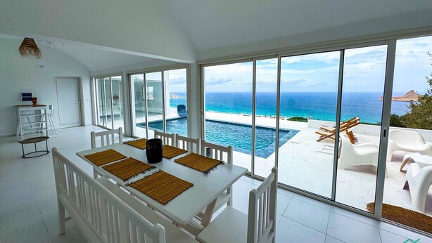Un comedor con vistas al océano y a una piscina.