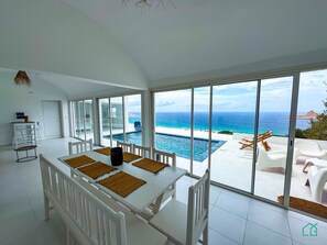 A dining area with a view of the ocean and a pool. - Padel Resort Villa Olivier (Raf Raf)