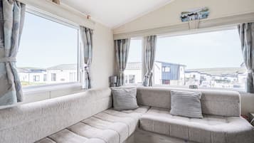 A cozy living room with a sectional sofa, large windows, and a view of the surrounding area.
