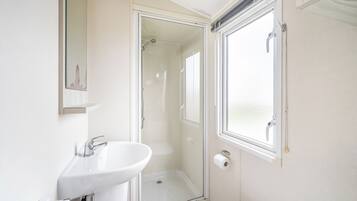 A bathroom with a glass shower enclosure, a white sink, and a toilet.