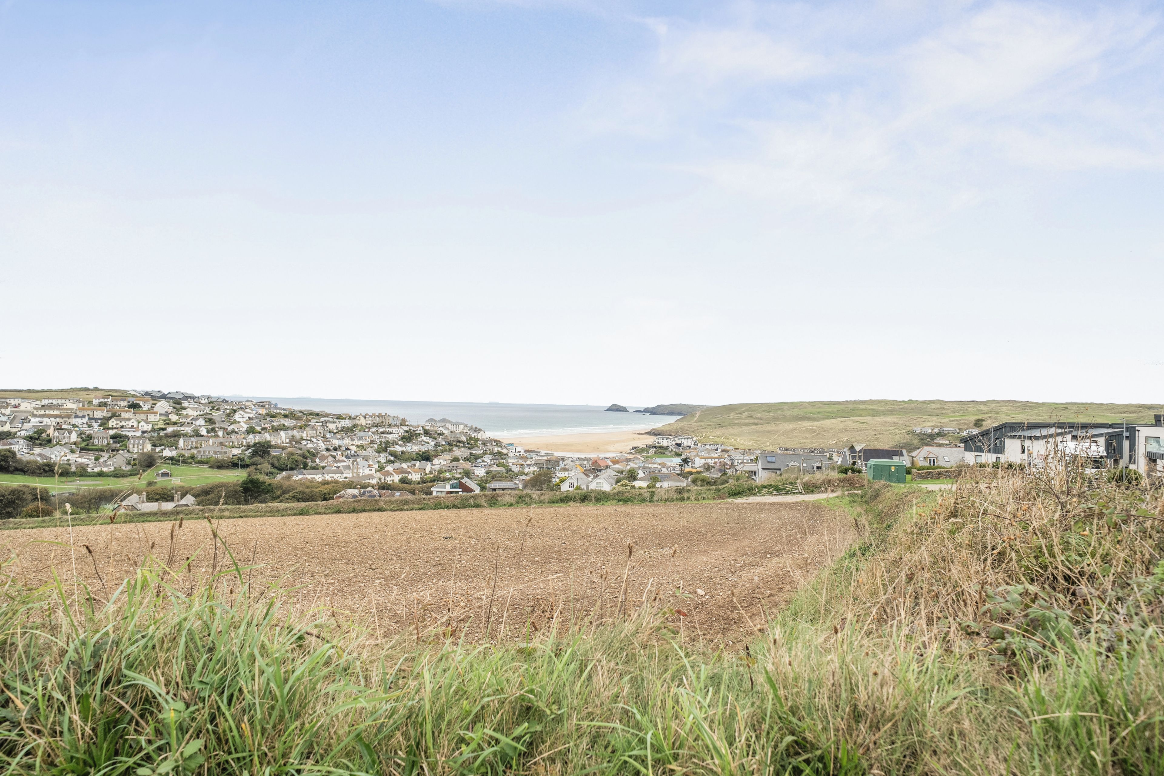 Eine Küstenstadt mit Strand, Häusern und einem Feld im Vordergrund.