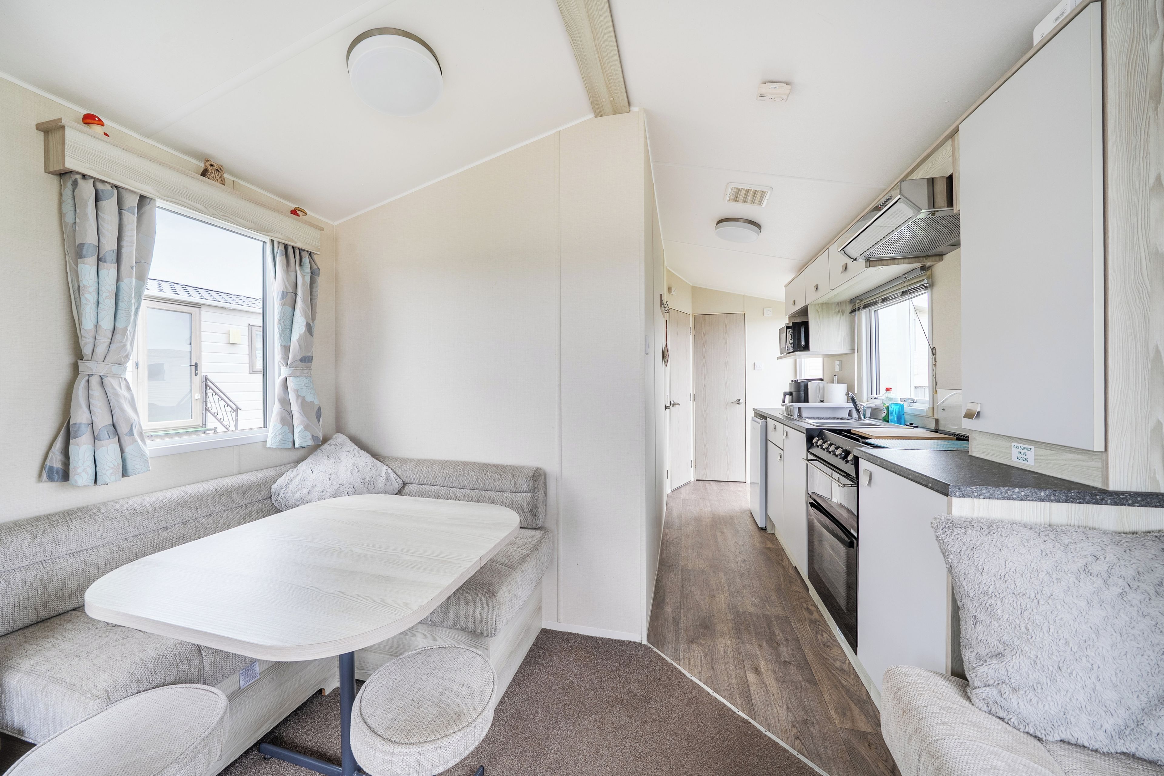 A compact RV interior with a kitchenette, a dining area, and a seating space.