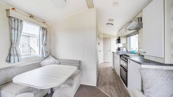 A compact RV interior with a kitchenette, a dining area, and a seating space.