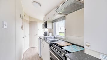 A compact kitchen with a stove, sink, and microwave.